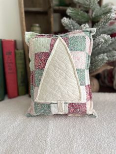 a decorative pillow with a quilted triangle on it sitting on a bed next to some books