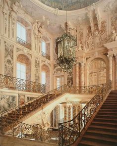 an ornately decorated staircase with chandelier and paintings on the walls