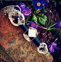 a close up of a metal object on a rock with flowers in the back ground