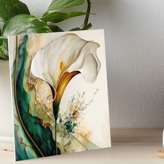 a white flower with green and gold details on it art boarder next to a potted plant