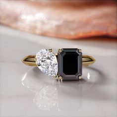 two engagement rings with an oval cut black and white diamond in the center, on a marble surface