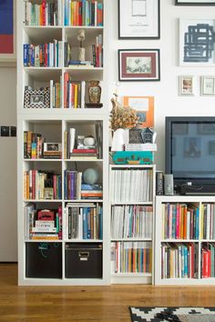 a bookshelf filled with lots of books next to a tv on top of a hard wood floor