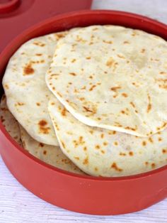 three tortillas in a red bowl on a white table