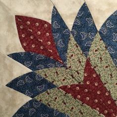 a close up of a quilt with red, white and blue flowers on it's center