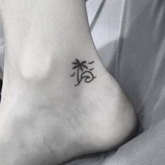 a small tattoo on the foot of a woman with a palm tree and wave design