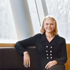 a woman sitting on top of a black couch next to a window in a room