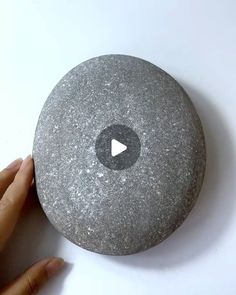 someone is holding up a rock with a play button on the top and bottom side