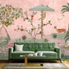 a living room with a green couch and pink wallpaper that has deers, flamingos, palm trees, and flowers on it