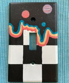 a black and white checkerboard light switch cover with colorful designs on the side