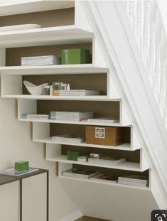 a white book shelf sitting under a stair case