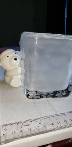 a glass bowl sitting on top of a table next to a plastic bear figurine