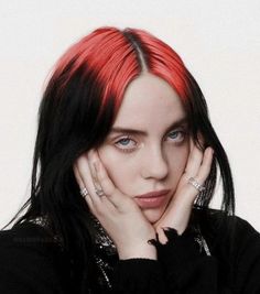 a woman with red hair and piercings posing for a photo in front of a white background