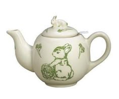 a white teapot with green rabbit designs on the side and a flower in the middle