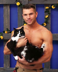 a shirtless man holding a black and white cat