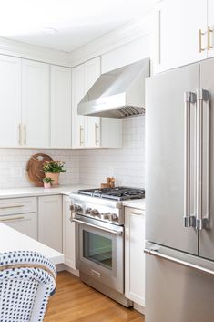 a kitchen with white cabinets, stainless steel appliances and wooden floors is pictured in this image