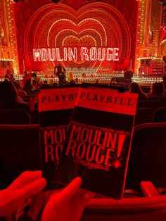 two people holding up their book covers in front of the stage at moulin roulee