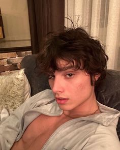 a young man sitting on top of a couch next to a pillow