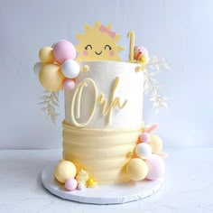 a white cake with yellow and pink decorations on it's top that says oh