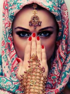 a woman wearing a veil and holding her hands to her face with jewelry on it