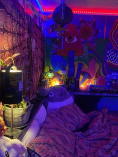 a bed room with a teddy bear sitting on it's side in front of a colorful wall