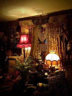 a living room filled with lots of furniture next to a lamp and window covered in curtains