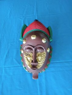 a brown mask with gold decorations on it's face sitting on a blue cloth