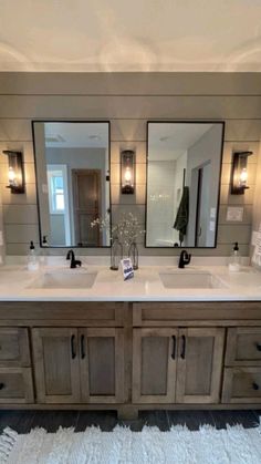 a bathroom with two sinks, mirrors and lights on the wall above it's counter