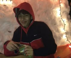 a man in a red and black hoodie is eating something out of a bag