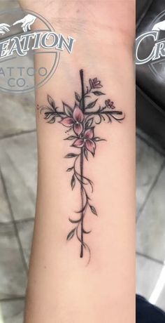 a cross tattoo with flowers on the wrist and an inscription that reads creation tattoo co