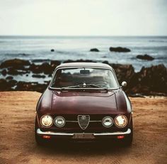 an old alfa coupe parked on the beach