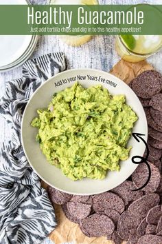 guacamole in a white bowl with crackers on the side next to it