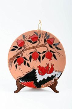 an ornament shaped like a vase with red flowers and leaves hanging from it