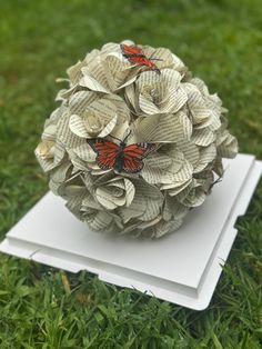 an origami ball with two butterflies on it sitting in the middle of some grass