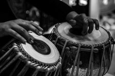 two hands on top of a drum with another hand holding the drum in black and white