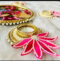 three decorative trays with rings and beads on white furnishing, one has a pink flower in the middle