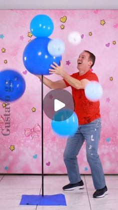 a man standing on top of a floor next to blue and white balloons in front of a pink wall