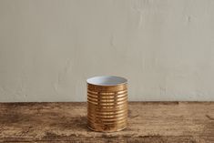 a white and gold vase sitting on top of a wooden table next to a wall