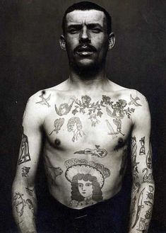 a man with lots of tattoos on his chest and arms, standing in front of a black background