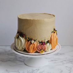 a cake with frosting and colorful flowers on it sitting on a white plate next to a marble counter top