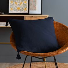 a chair with a black pillow on top of it next to a wooden table and framed pictures