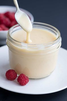 a spoon full of yogurt with raspberries on the side