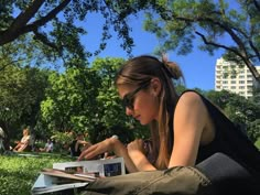 a woman sitting on the grass reading a book