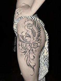 a woman's thigh with a bird and flowers tattoo on her leg, in black and white