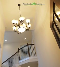 a chandelier hanging from the ceiling in a room with white walls and stairs