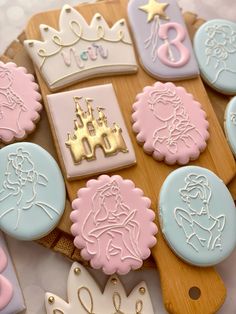 decorated cookies are arranged on a cutting board with royal emblems and tiara decorations