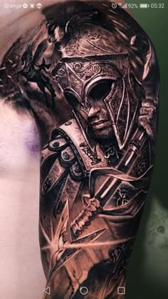 a man's arm with tattoos on it and an image of a warrior in the background