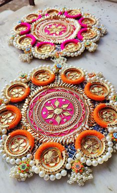 two colorfully decorated trays sitting on top of a white table covered in beads