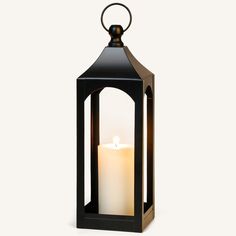 a black lantern with a lit candle in the middle and one light on it's side