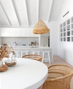 a white kitchen with wicker chairs and an island in the middle is featured on instagram