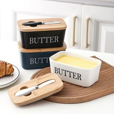 two butter dishes and a croissant on a plate with the word butter in it